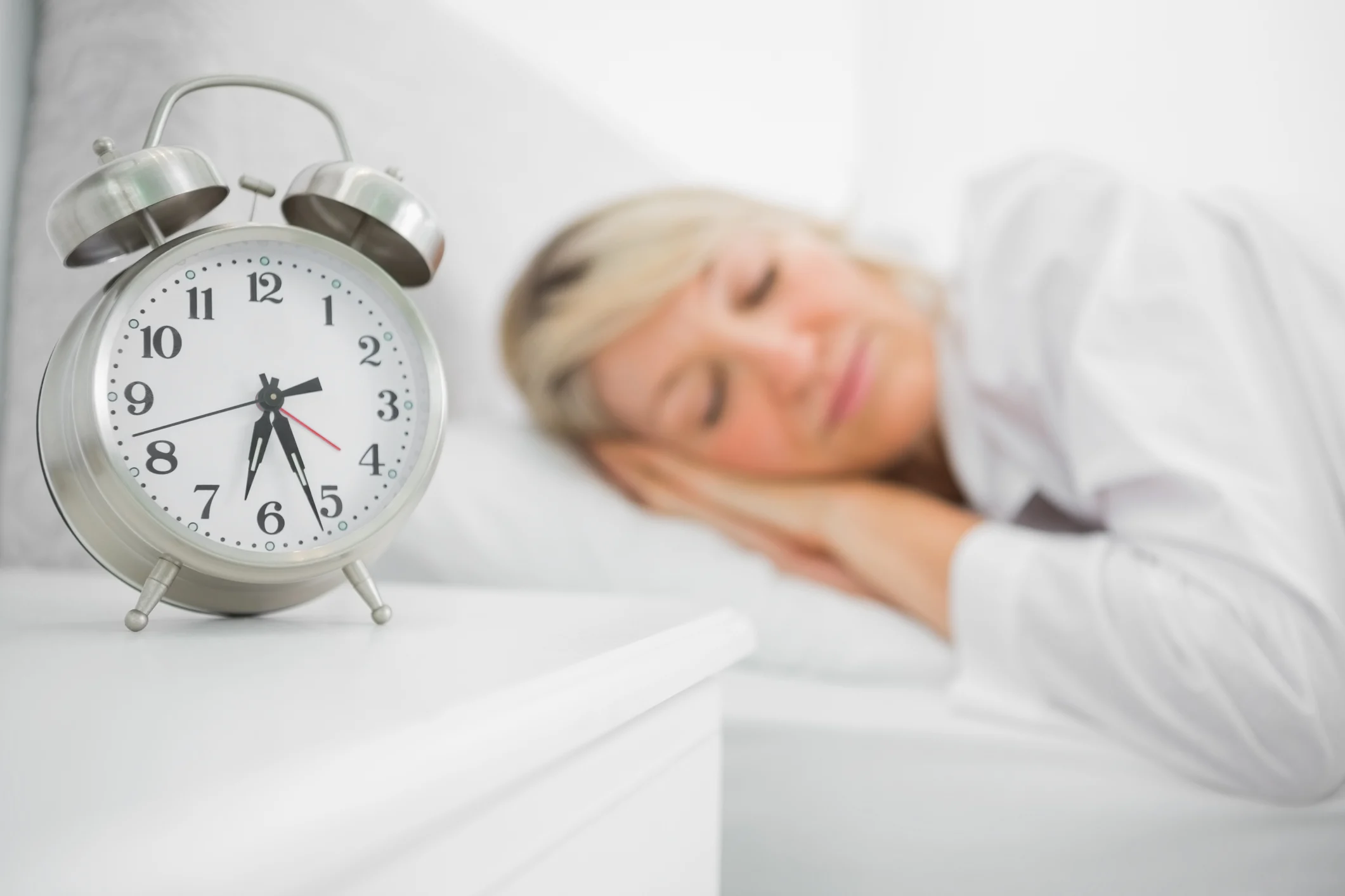 Woman sleeping with alarm clock next to her